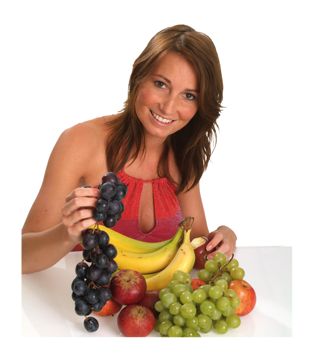 Jonge vrouw zittend voor een tafel met daarop druiven, bananen en rode appels